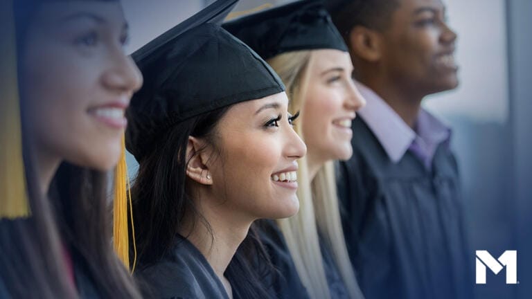 Students in profile at graduation wearing traditional cap and gown and looking up and to the right.